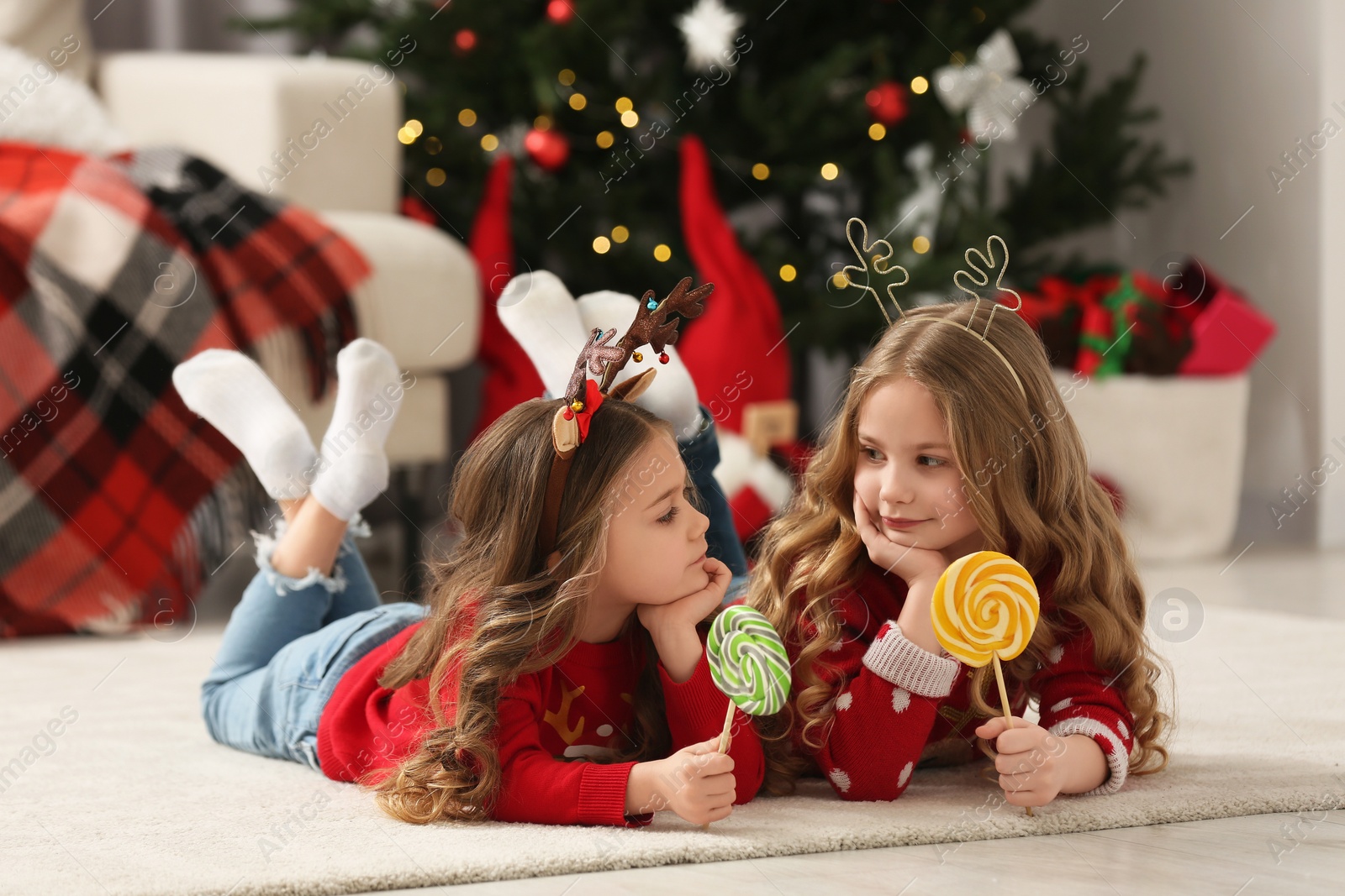 Photo of Cute little girls with lollipops at home. Christmas atmosphere