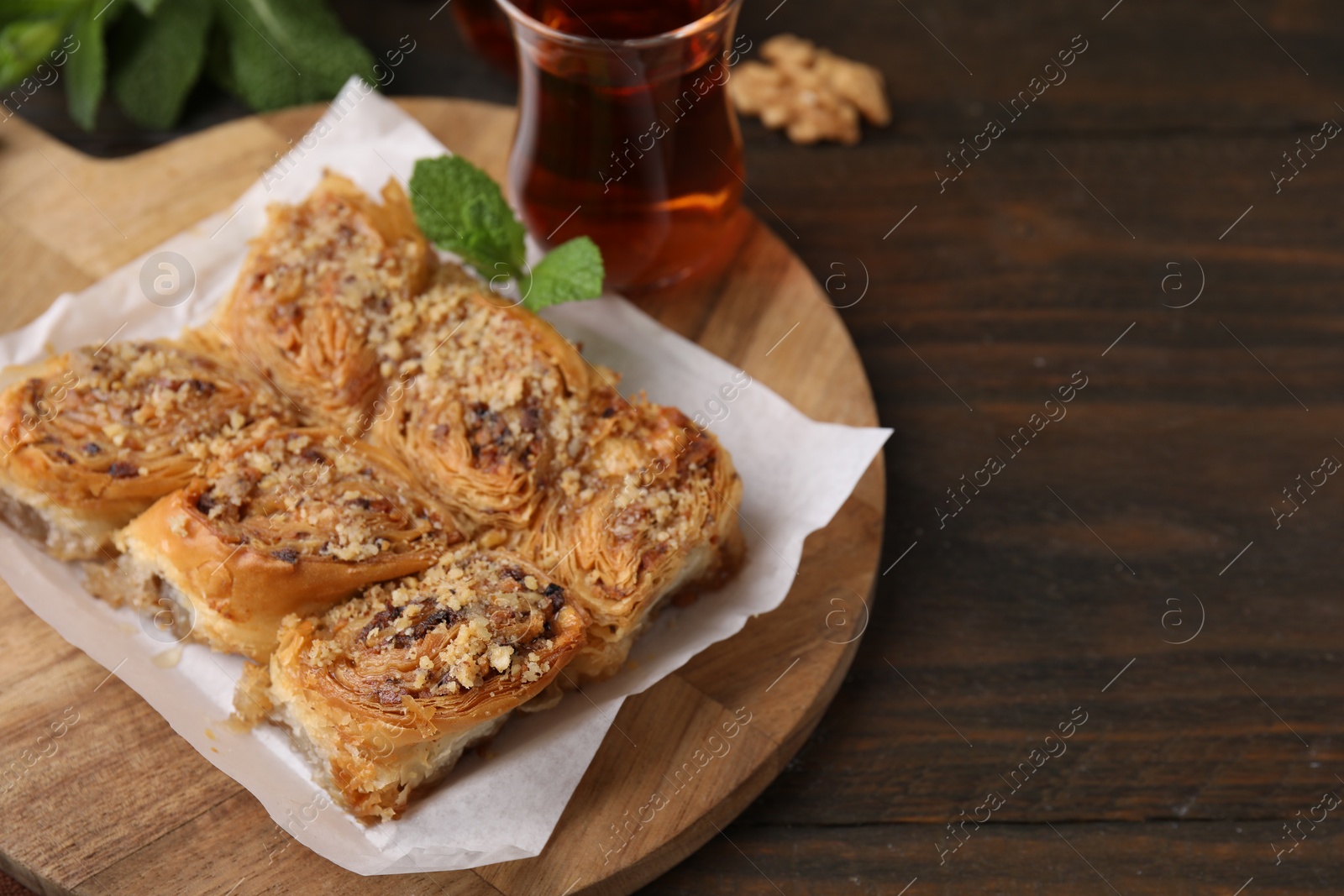 Photo of Eastern sweets. Pieces of tasty baklava and tea on wooden table, closeup. Space for text