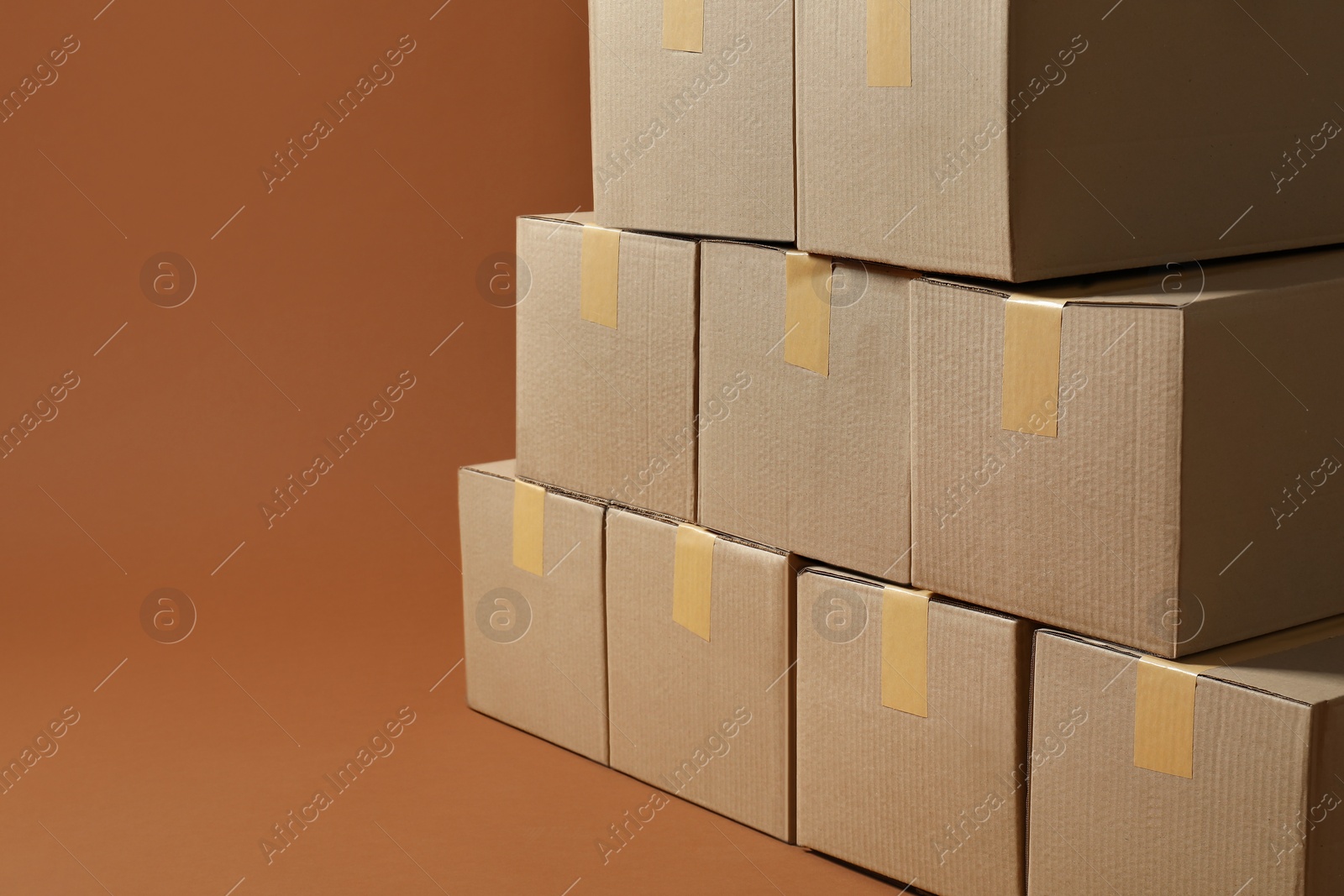 Photo of Stack of many cardboard boxes on brown background, space for text