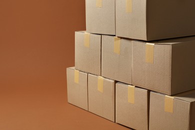 Stack of many cardboard boxes on brown background, space for text