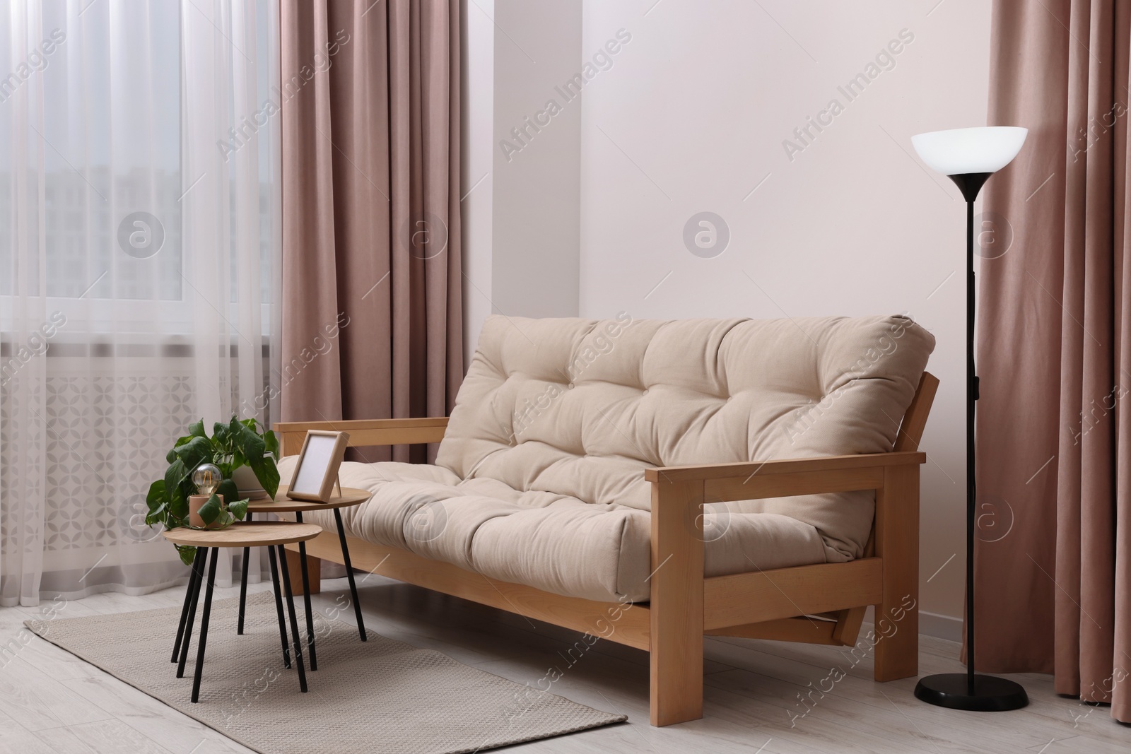 Photo of Comfortable sofa and houseplant on coffee table in light room. Interior design