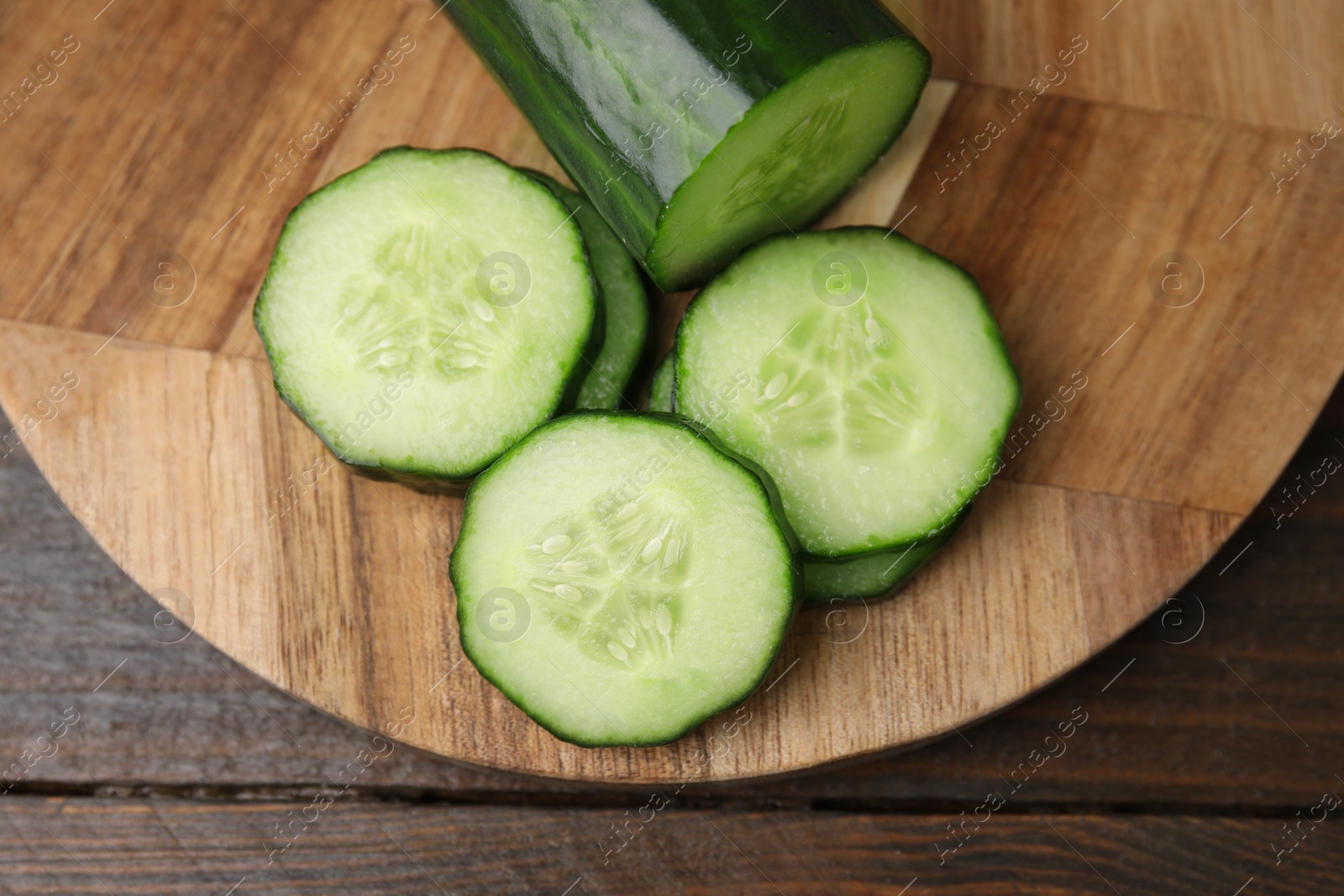 Photo of Fresh cut cucumber on wooden table, top view