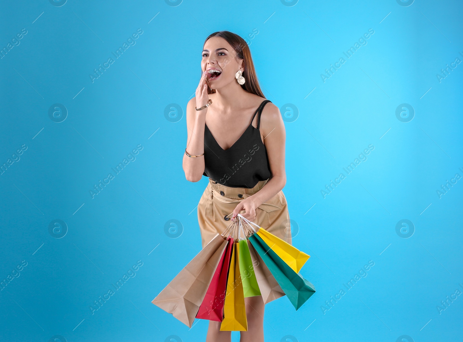 Photo of Young woman with shopping bags on color background