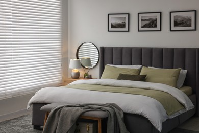 Window with horizontal blinds and comfortable bed in room