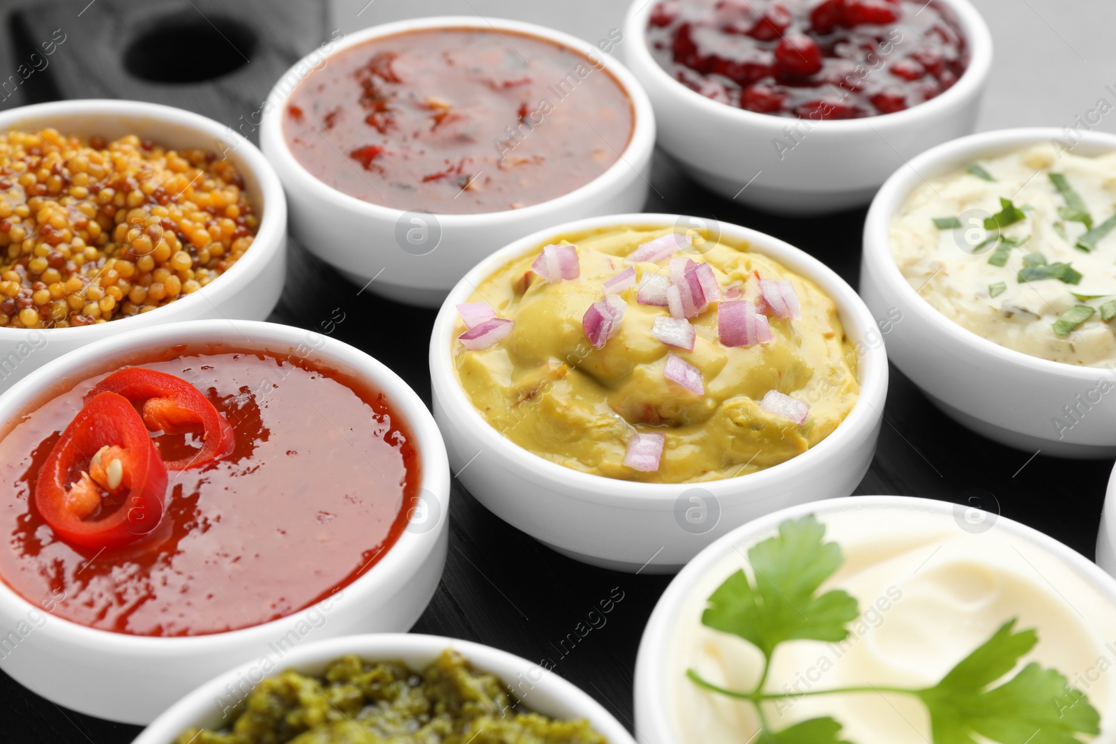 Photo of Different tasty sauces in bowls on board, closeup