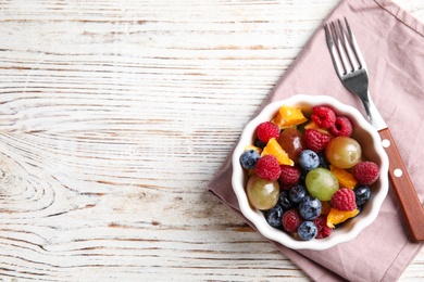 Photo of Fresh tasty fruit salad on white wooden table, flat lay. Space for text