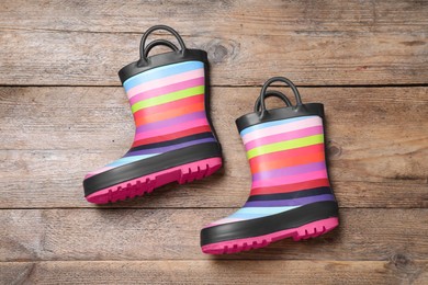 Photo of Pair of striped rubber boots on wooden background, top view