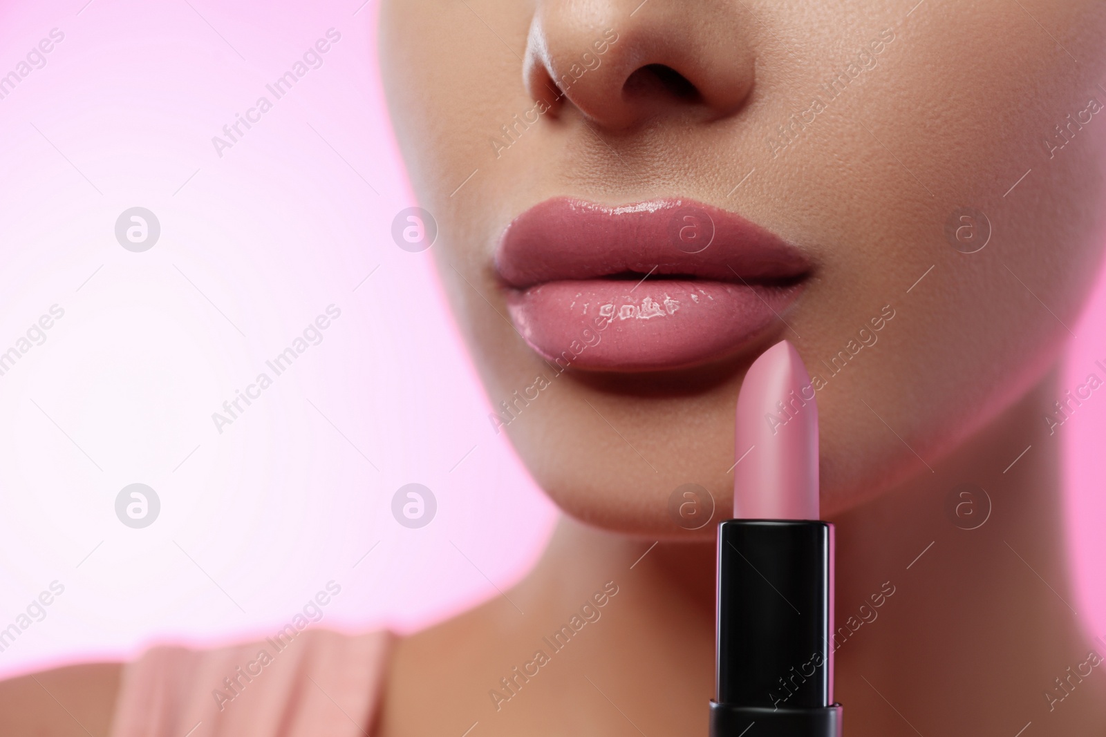 Photo of Woman with glossy lipstick on pink background, closeup