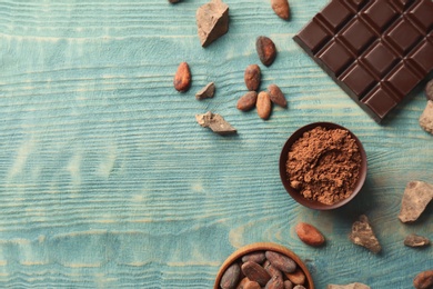 Flat lay composition with cocoa powder and chocolate bar on wooden background