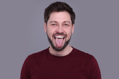 Photo of Happy man showing his tongue on light grey background