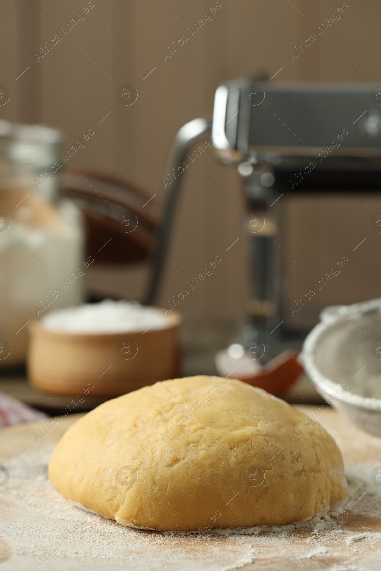 Photo of Raw dough for pasta and flour on table, closeup