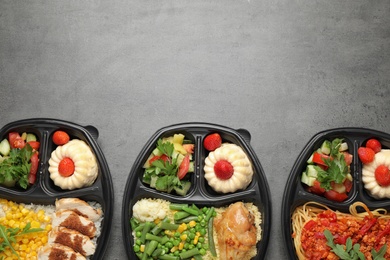 Photo of Top view of lunchboxes with different meals on grey table, space for text. Healthy food delivery