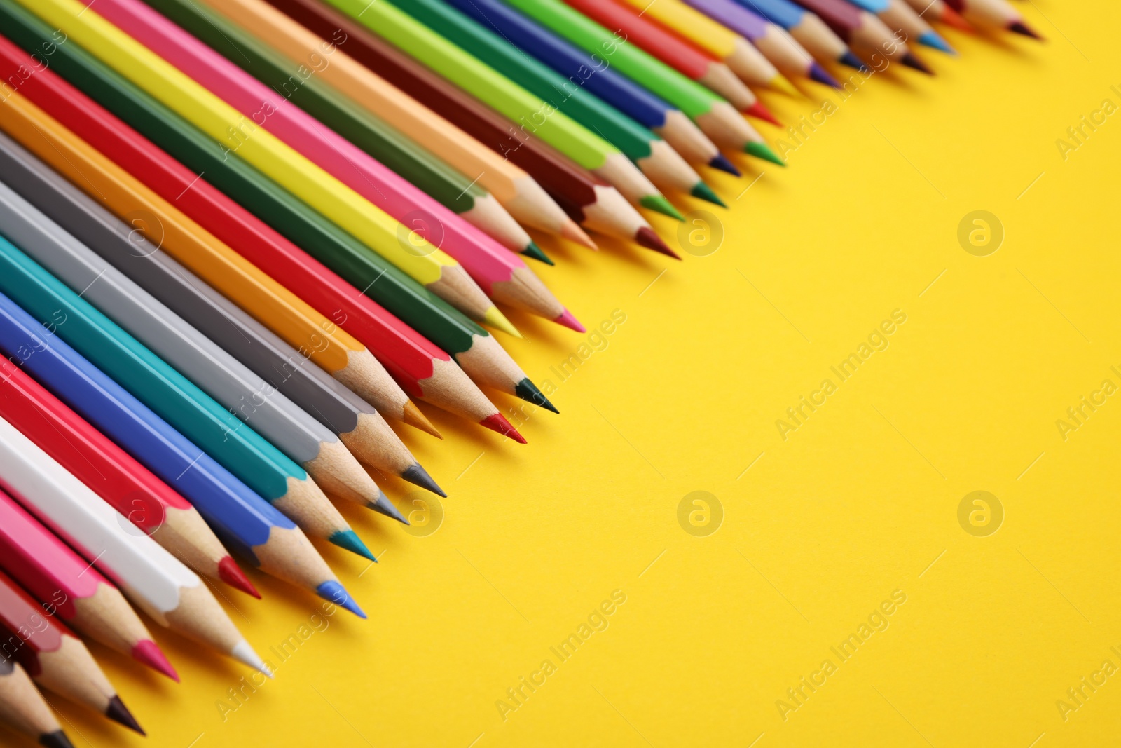 Photo of Colorful wooden pencils on yellow background, closeup. Space for text