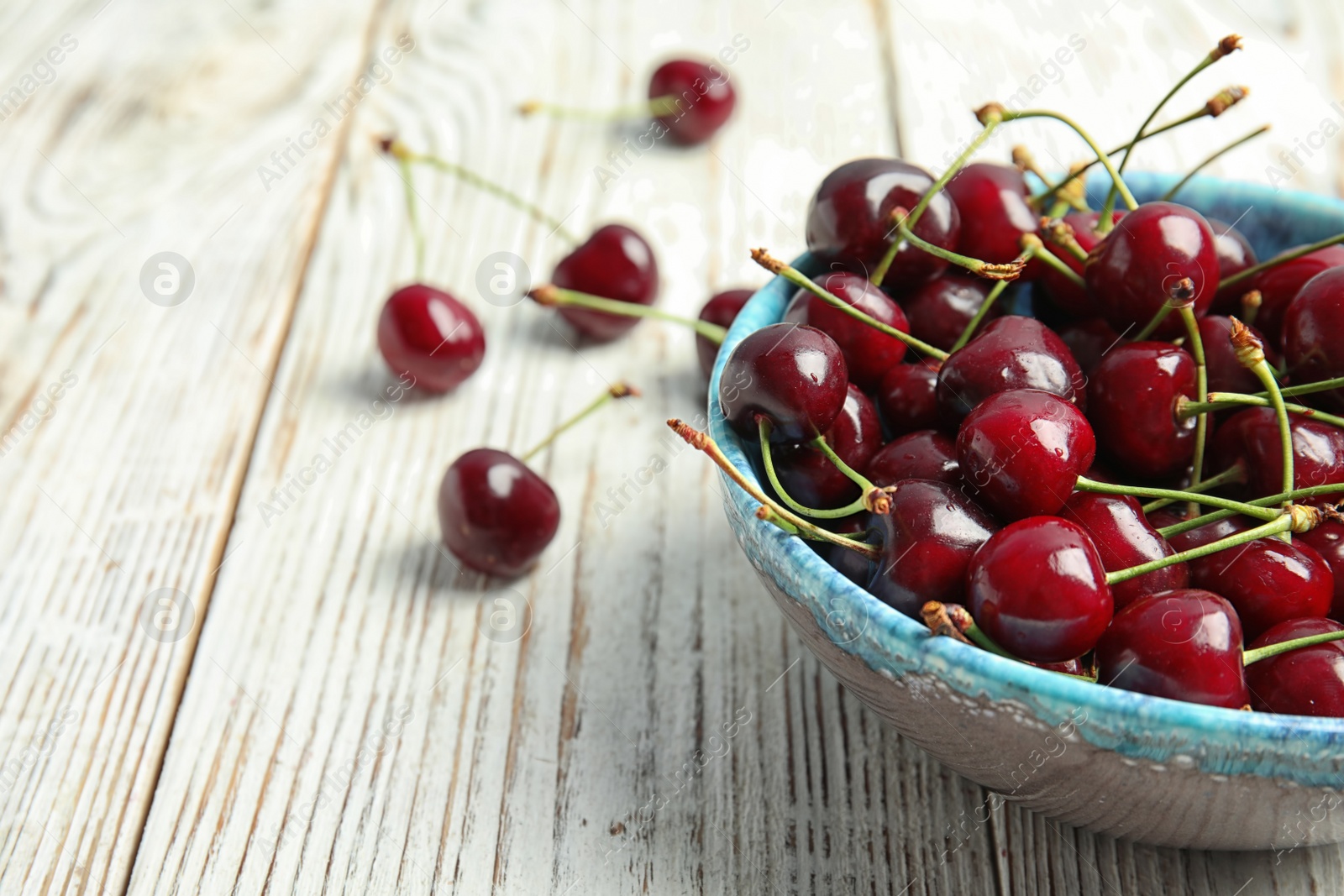 Photo of Bowl with sweet red cherries on wooden table