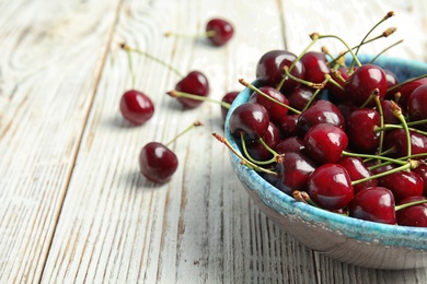 Photo of Bowl with sweet red cherries on wooden table