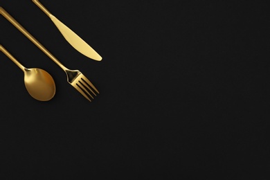 Photo of Luxury gold cutlery on black background, top view with space for text
