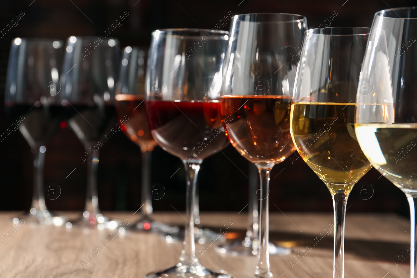 Photo of Different tasty wines in glasses on wooden table