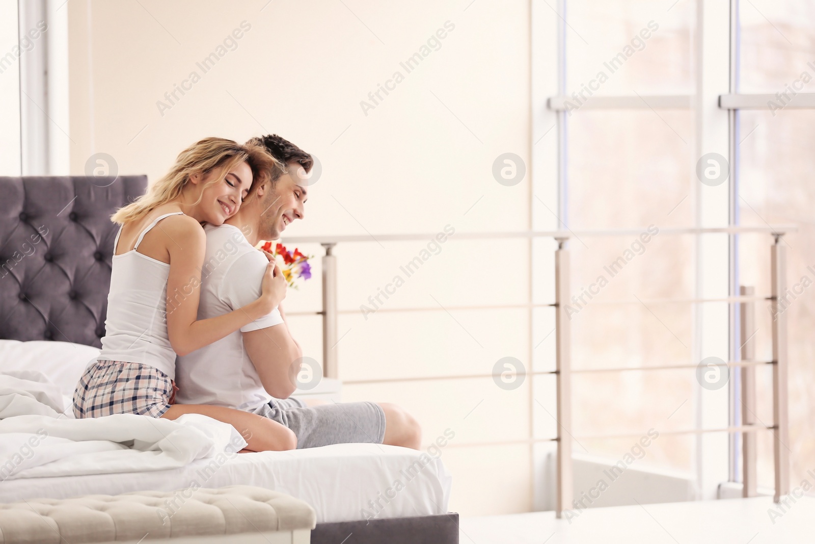 Photo of Young couple hugging on bed at home