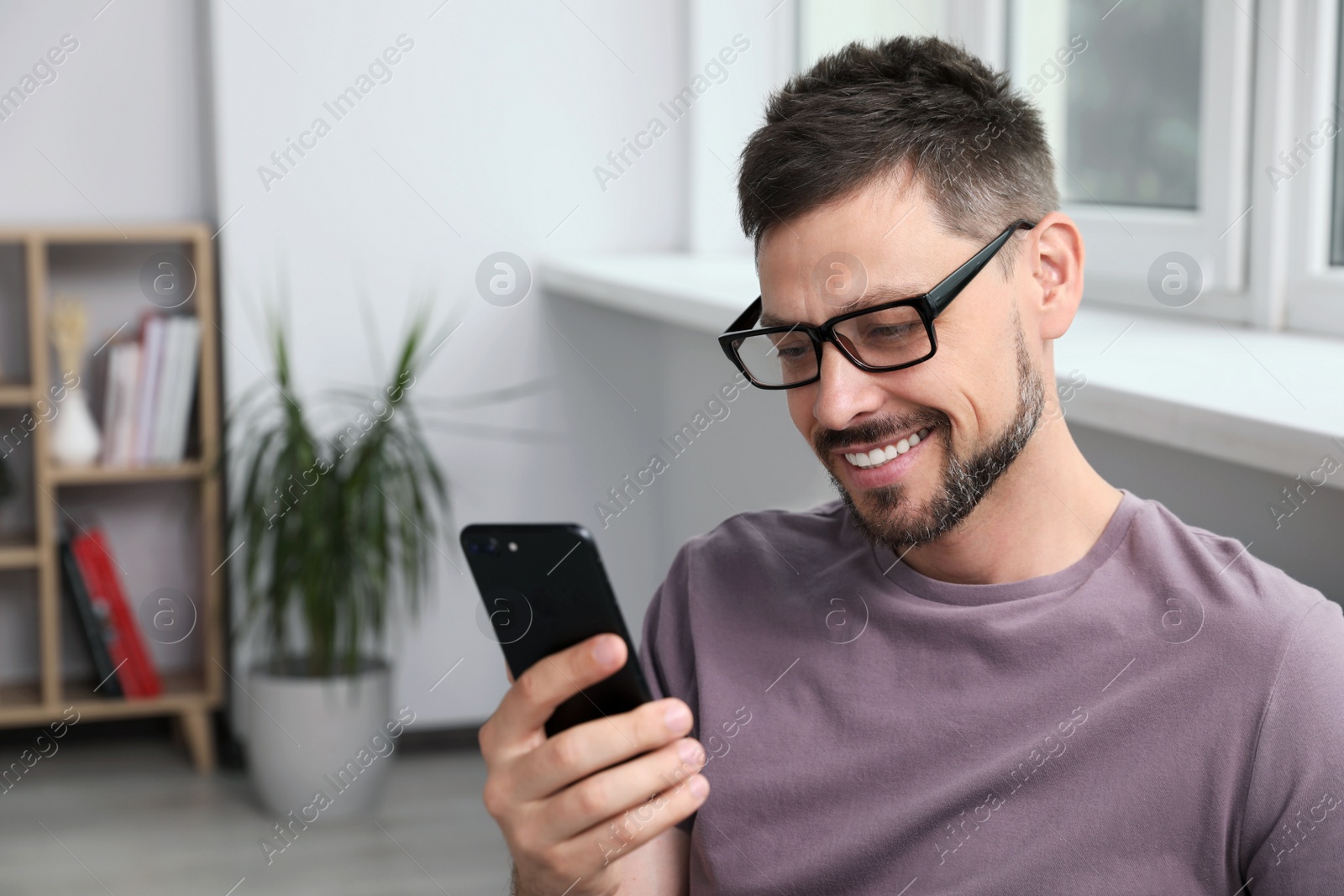 Photo of Happy handsome man using smartphone at home