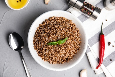 Flat lay composition with bowl of buckwheat porridge served on grey table