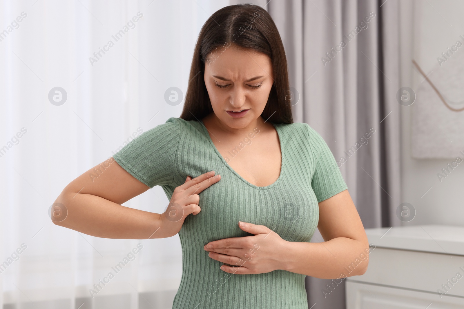 Photo of Mammology. Young woman doing breast self-examination at home