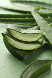 Photo of Fresh aloe vera pieces on green background, closeup