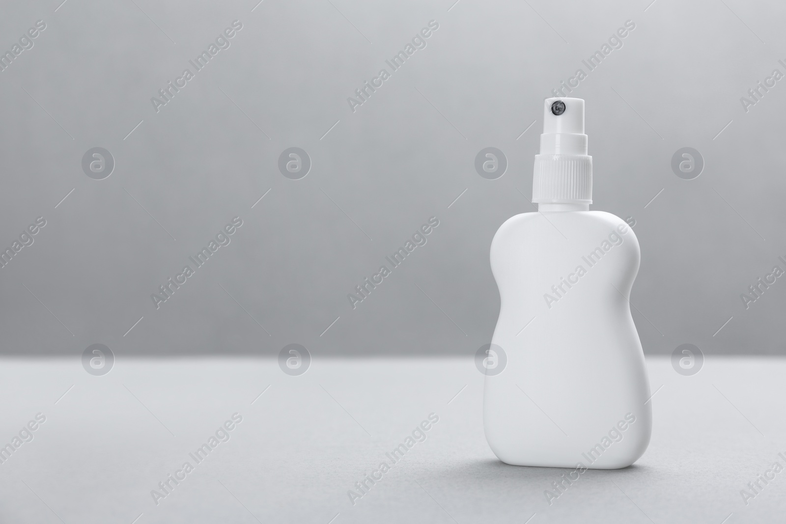 Photo of Bottle with insect repellent spray on grey background, space for text