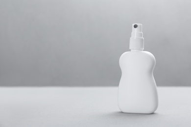 Photo of Bottle with insect repellent spray on grey background, space for text