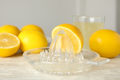 Photo of Plastic juicer with half of lemon on white wooden table