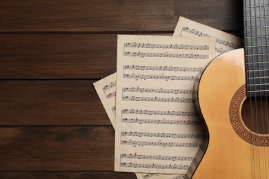 Photo of Composition with guitar and music notations on wooden table, flat lay. Space for text