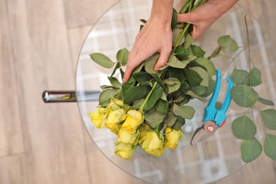 Photo of Female florist making beautiful bouquet in flower shop, top view