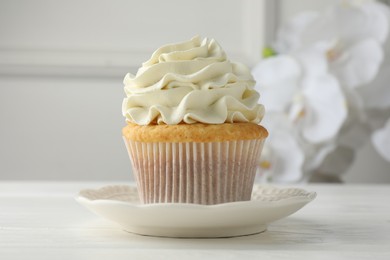 Photo of Tasty vanilla cupcake with cream on white table, closeup