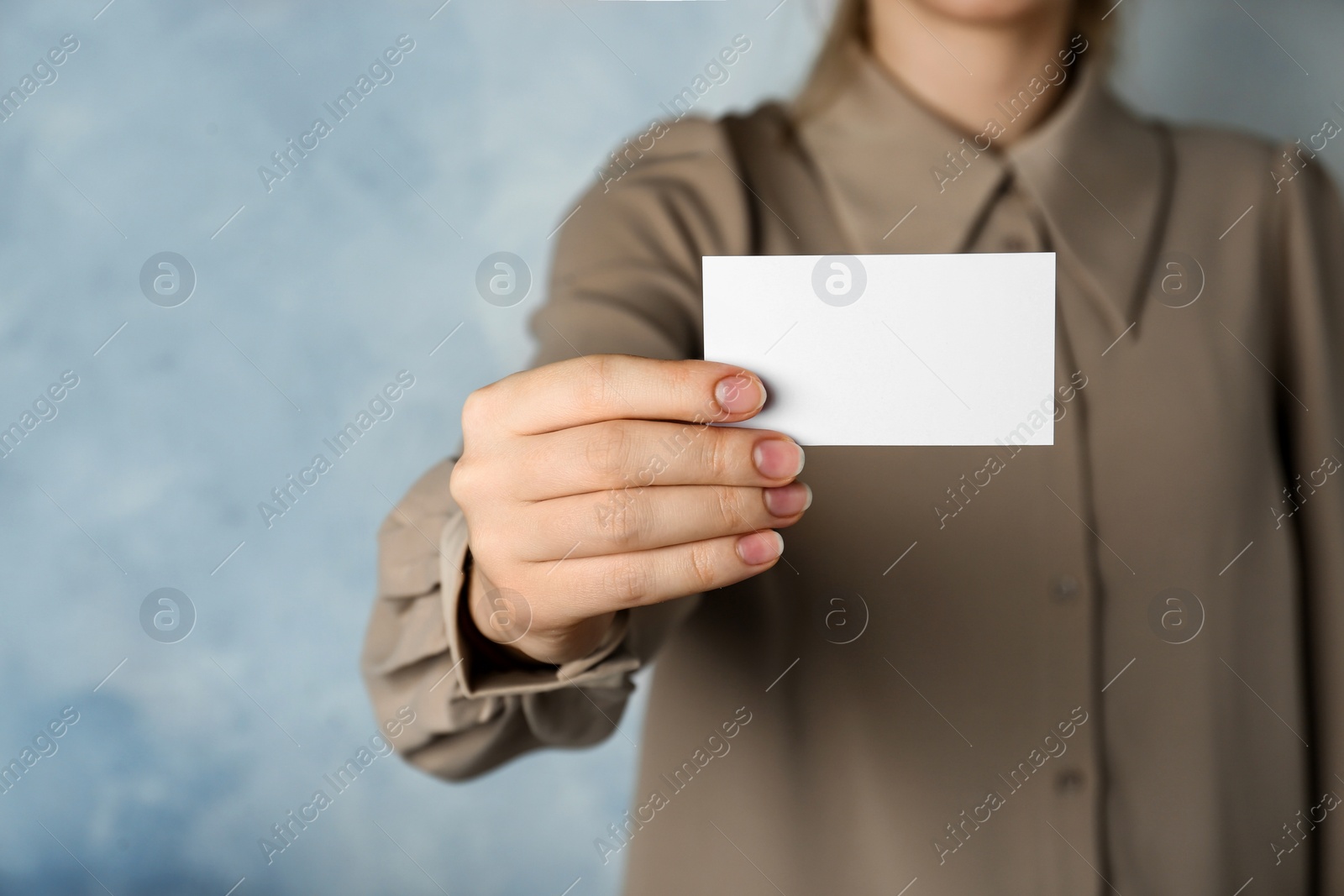 Photo of Woman holding blank business card on light blue background, closeup. Mockup for design