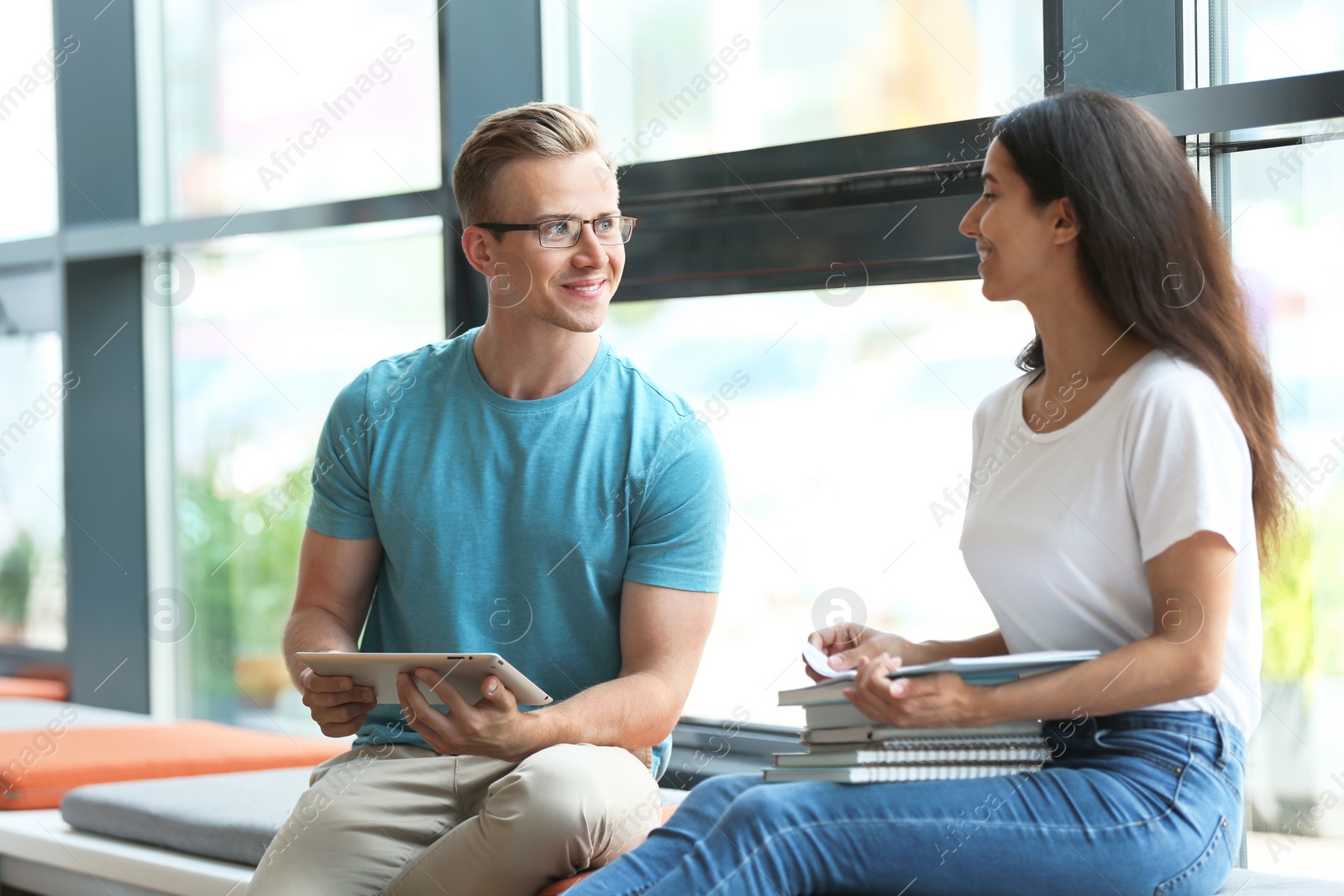 Photo of Young people talking near window in library