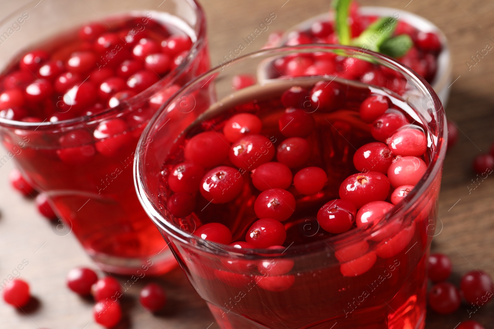Photo of Tasty cranberry juice in glasses and fresh berries on wooden table, closeup