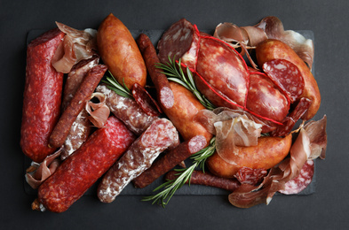 Photo of Different types of sausages served on black background, flat lay