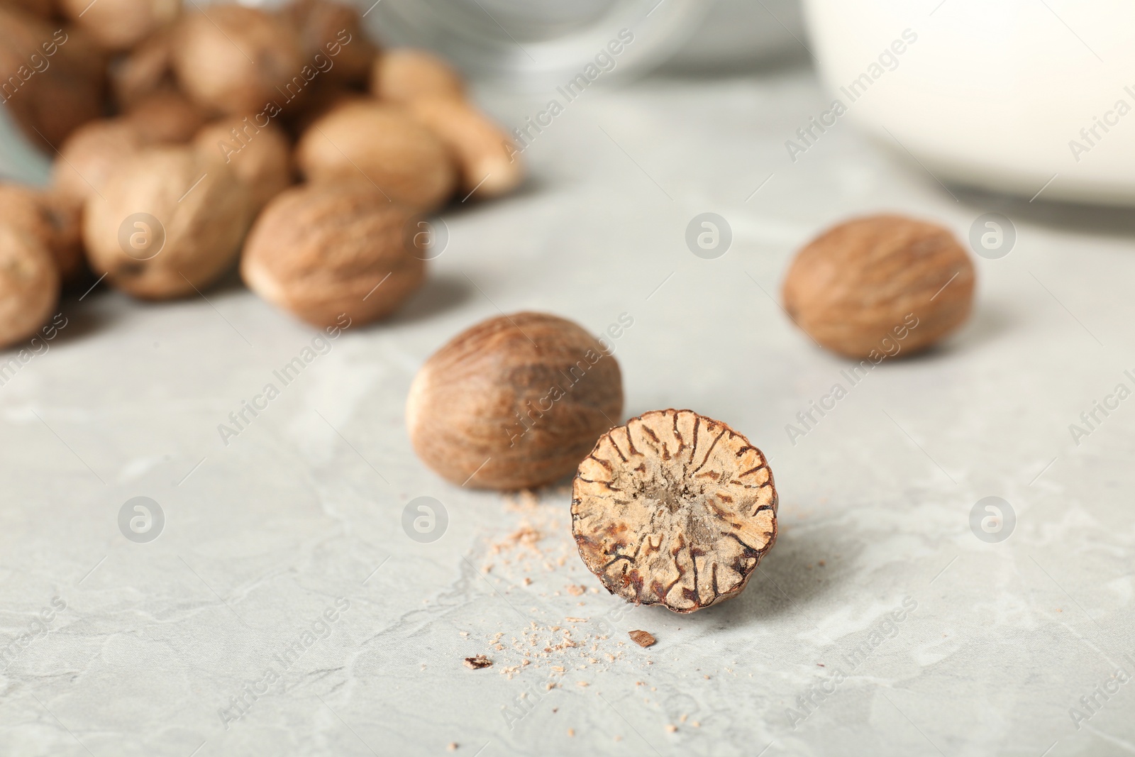 Photo of Whole and cut nutmeg seeds on light marble table