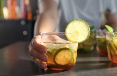 Woman with glass of delicious mint julep cocktail at table, closeup