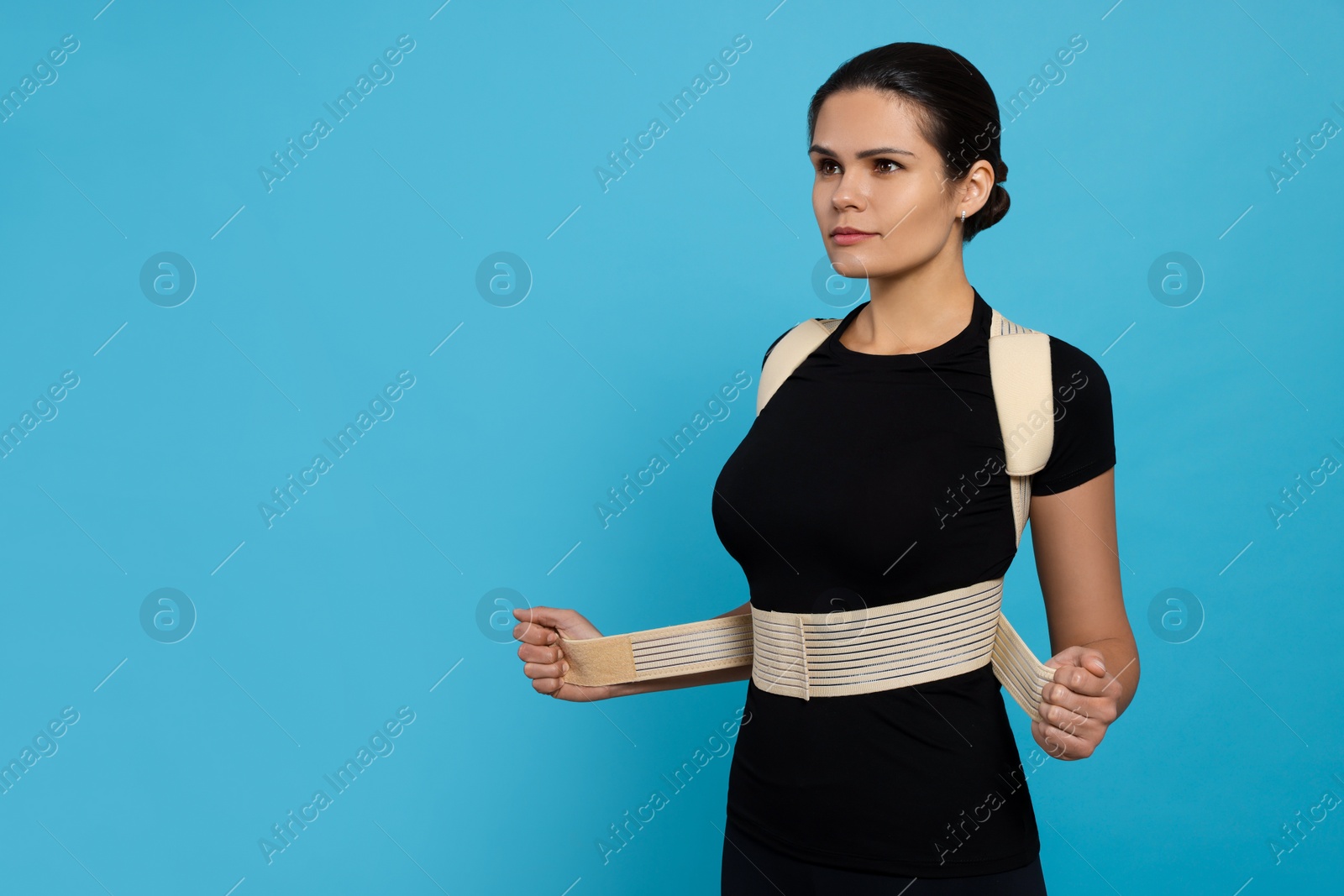 Photo of Beautiful woman with orthopedic corset on blue background, space for text