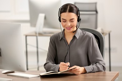 Hotline operator with headset and notebook working in office