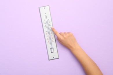 Photo of Woman with weather thermometer on lilac background, top view