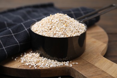 Photo of Raw barley groats in scoop on table, closeup