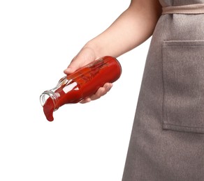 Woman pouring tasty ketchup from bottle on white background, closeup