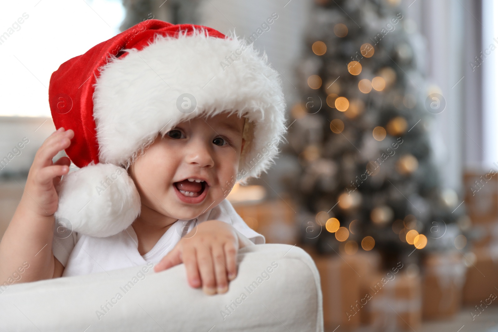 Image of Cute little baby wearing Santa hat at home. Christmas celebration