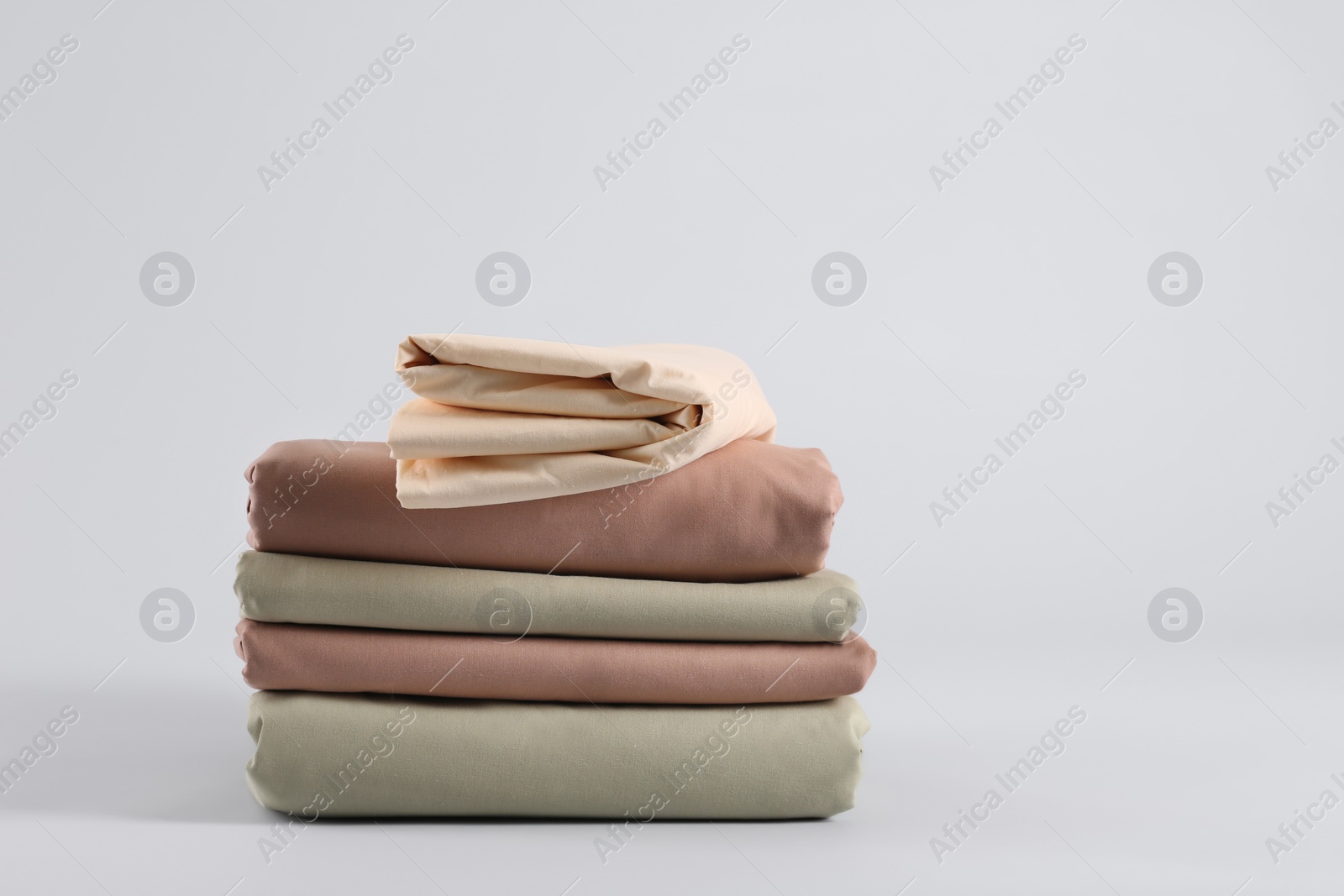 Photo of Stack of clean bed sheets on white background