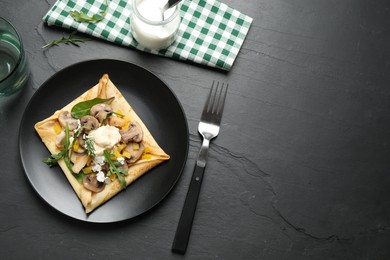 Photo of Delicious breakfast with thin pancakes on black table, flat lay