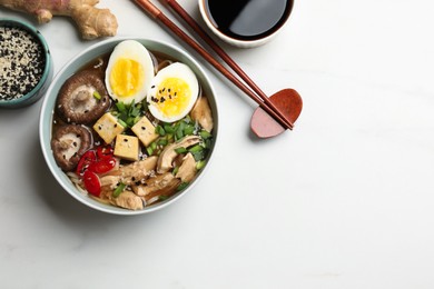 Delicious ramen served on white table, flat lay with space for text. Noodle soup