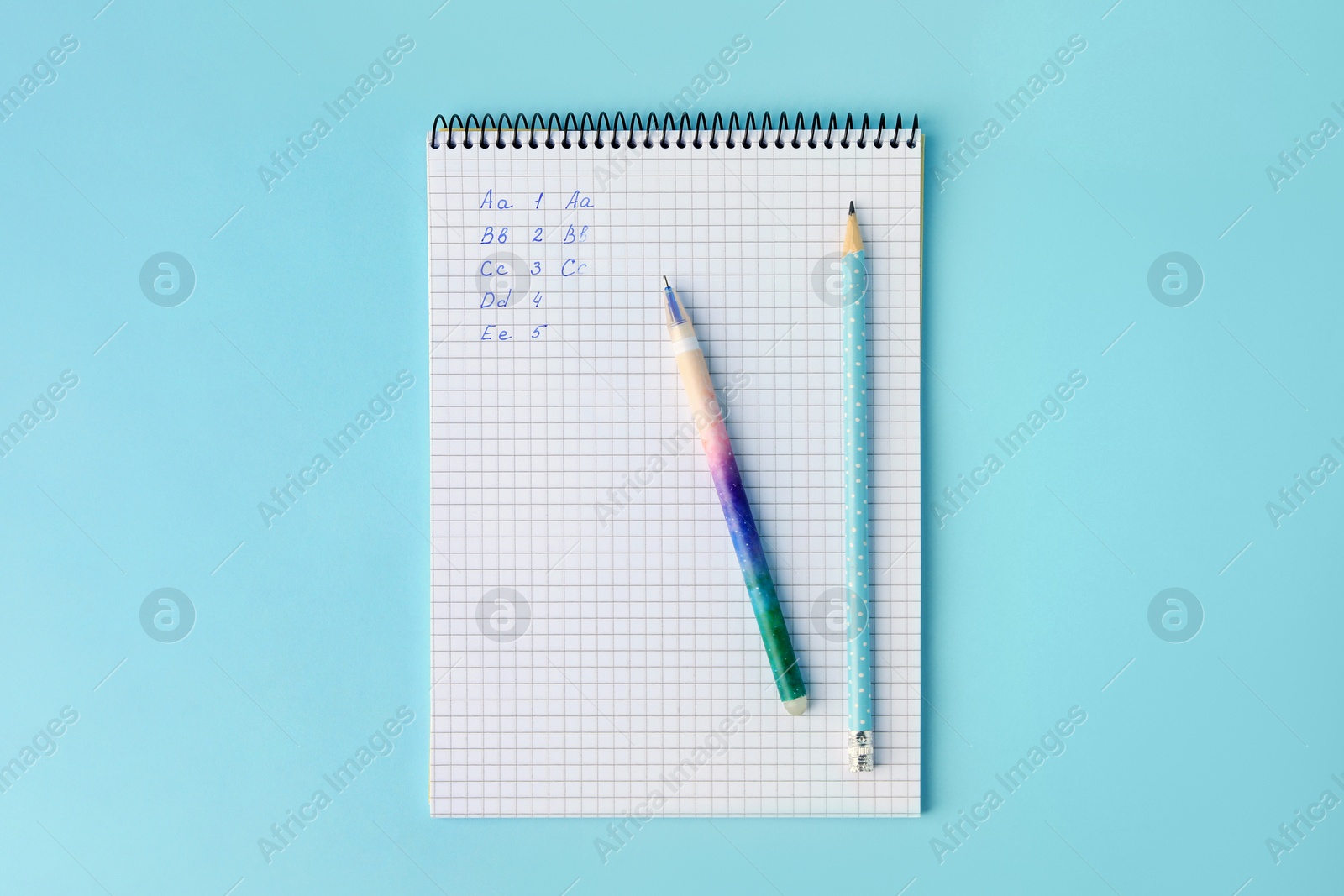 Photo of Letters and numbers written in notepad with erasable pens on light blue background, top view
