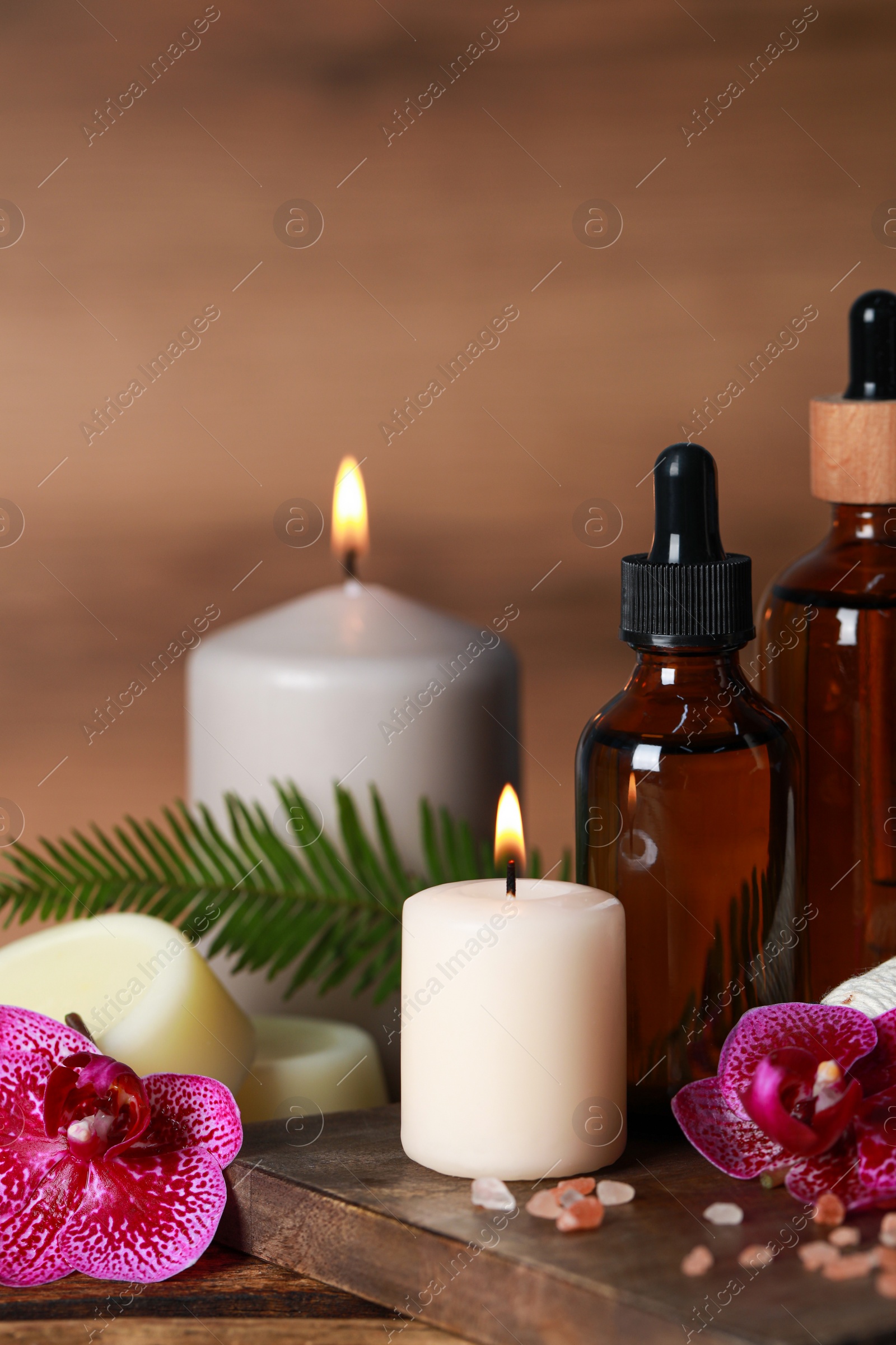 Photo of Beautiful spa composition with different care products and burning candles on wooden table