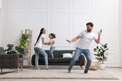 Photo of Happy family dancing and having fun in living room